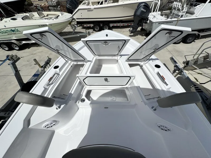 Slide: The Image of 2025 Sportsman Masters 247 Bay Boat with open storage compartments, docked among other boats. - 10