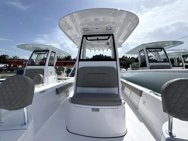 Slide: The Image of 2025 Sportsman Masters 247 Bay Boat interior with seating and console under a clear sky. - 12