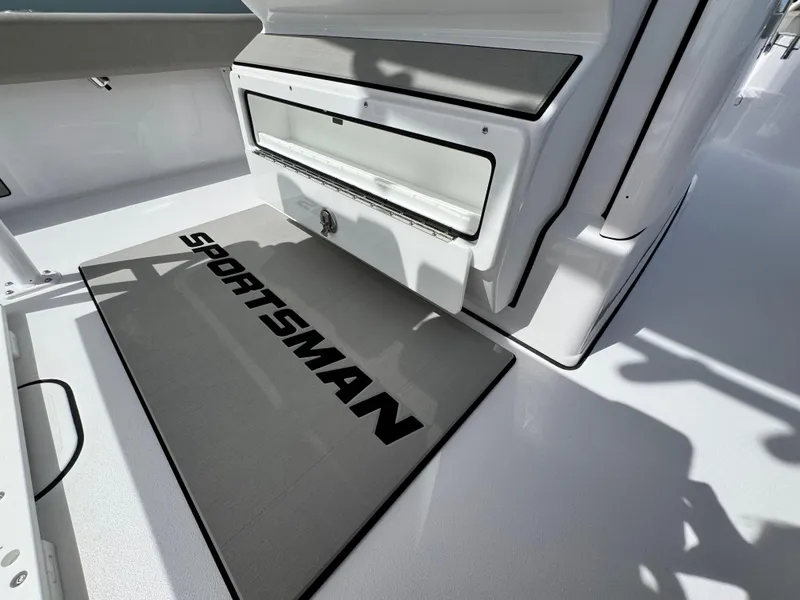 Slide: The Image of 2025 Sportsman Masters 247 Bay Boat interior with open storage compartment and branded mat. - 23