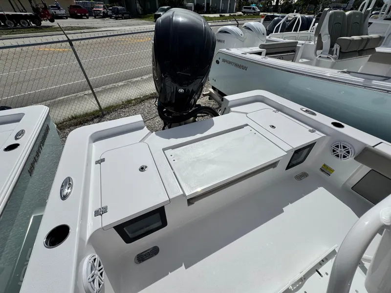 Slide: The Image of 2025 Sportsman Masters 247 Bay Boat with outboard motor, docked near a fence. - 25