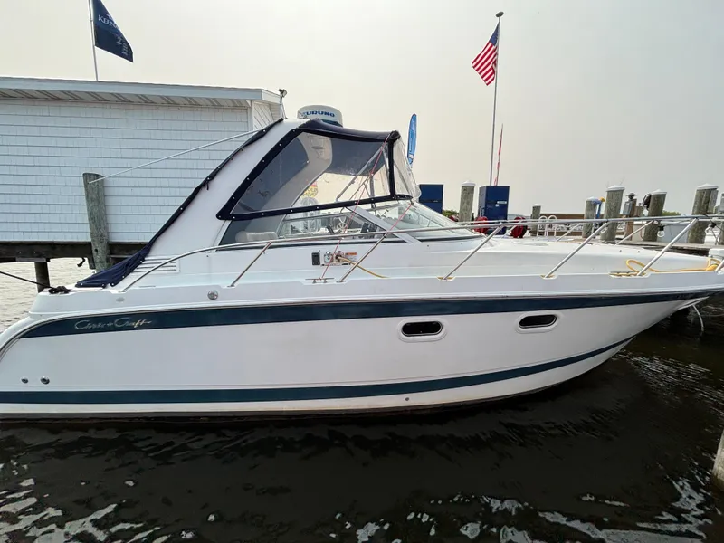 The Image of 1999 Chris-Craft 300 Express Cruiser docked near flags and building. - 0