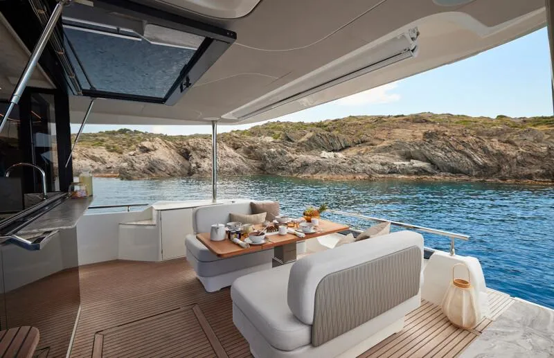 Slide: The Image of Luxurious Prestige F5.7 yacht interior with dining setup, overlooking serene coastal waters, 2026 model. - 17