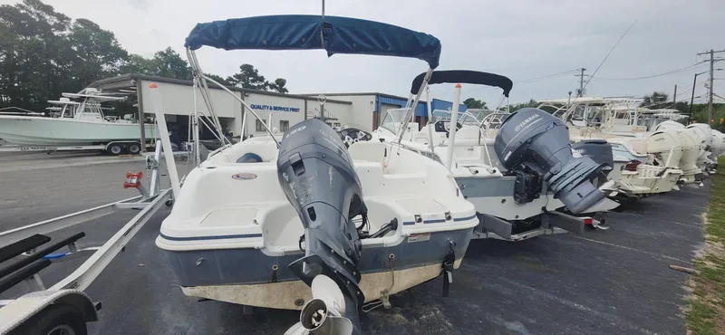 Slide: The Image of 2013 Hurricane SunDeck Sport 201 OB boat with outboard motor, parked in a marina. - 2