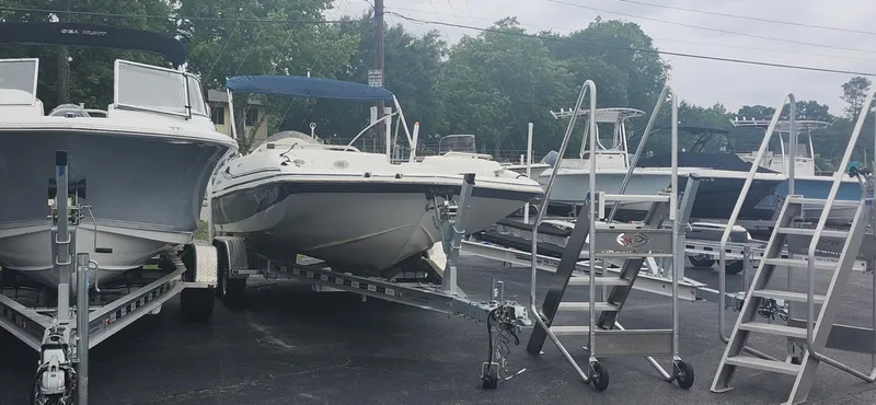 Slide: The Image of 2013 Hurricane SunDeck Sport 201 OB boat on trailer, surrounded by other boats and ladders. - 4