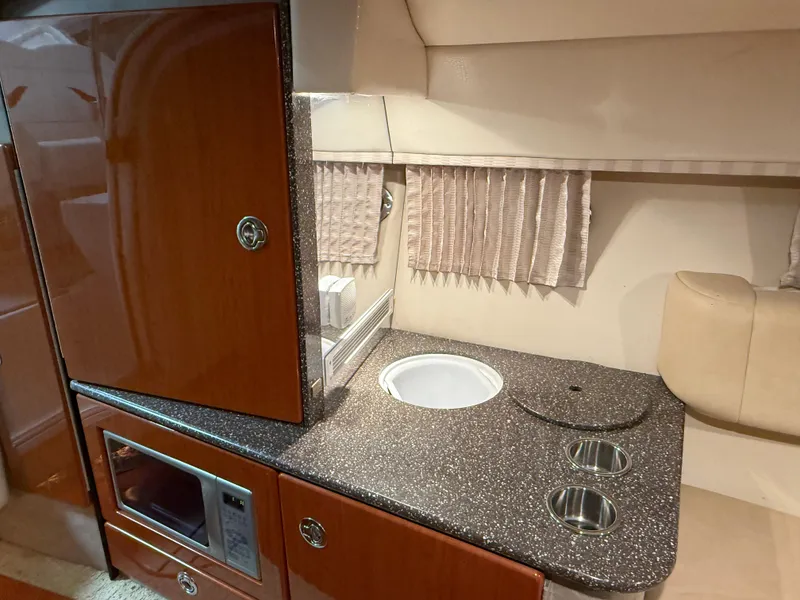 Slide: The Image of 2008 Formula 330 Sun Sport interior with kitchenette, featuring sink, microwave, and storage cabinets. - 31