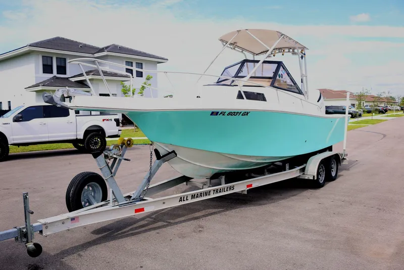 The Image of 1990 Mako 230 Walk Around boat on trailer, parked in residential area. - 1