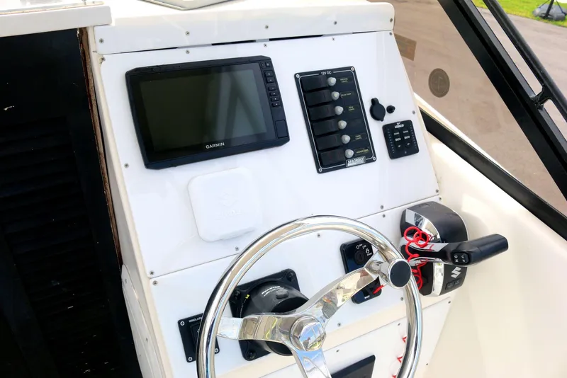 Slide: The Image of 1990 Mako 230 Walk Around boat dashboard with steering wheel and control panel. - 10