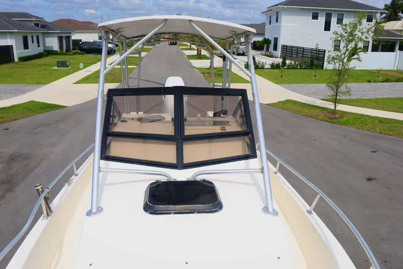 Slide: The Image of 1990 Mako 230 Walk Around boat on residential street, showcasing bow and windshield. - 12