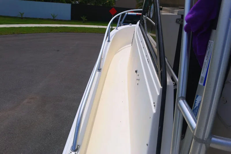 Slide: The Image of 1990 Mako 230 Walk Around boat deck with railing, parked on pavement. - 15