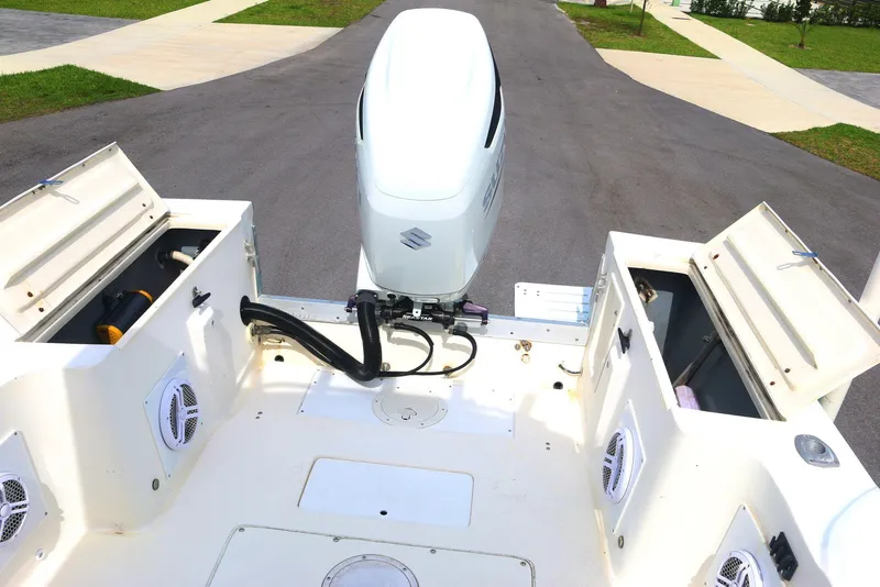 Slide: The Image of 1990 Mako 230 Walk Around boat with open storage compartments and outboard motor. - 18