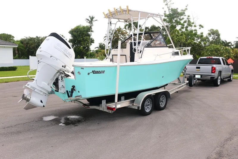 Slide: The Image of 1990 Mako 230 Walk Around boat on trailer, parked near a truck. - 20