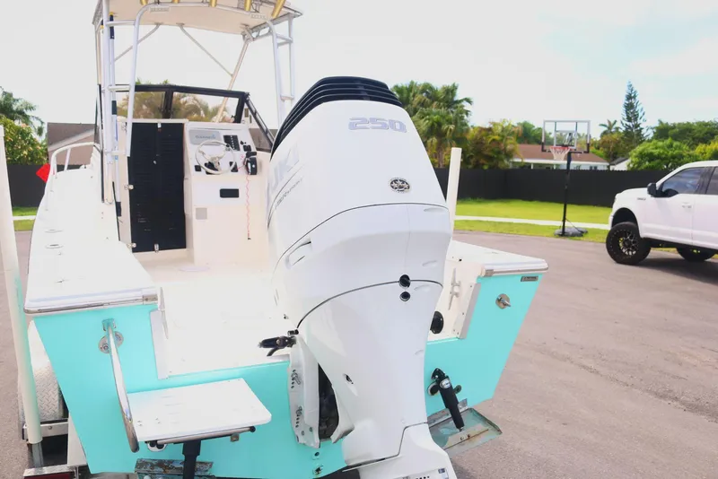 Slide: The Image of 1990 Mako 230 Walk Around boat with powerful outboard motor, parked on a driveway. - 3