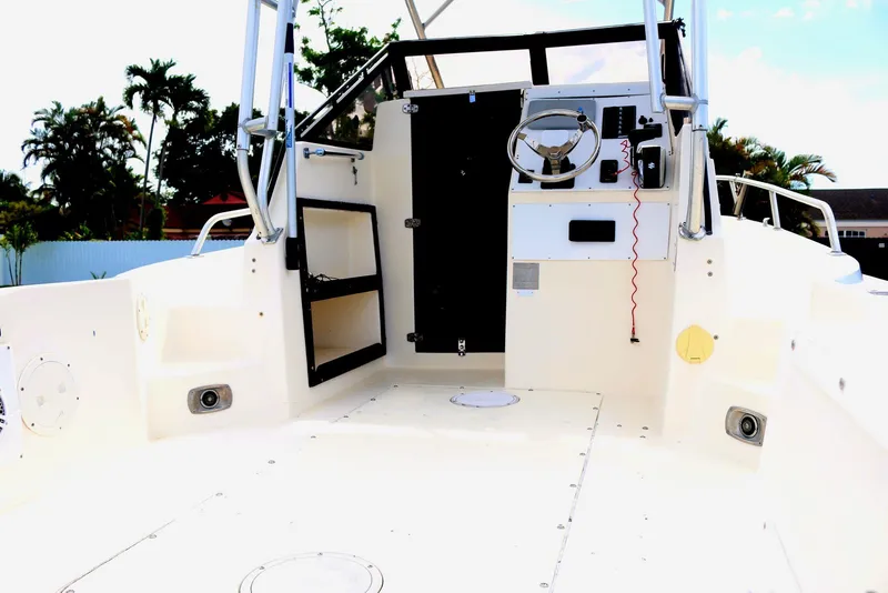 Slide: The Image of 1990 Mako 230 Walk Around boat interior with steering wheel and open cabin door. - 6