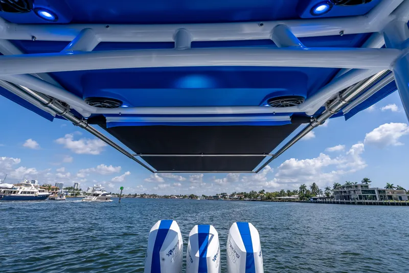 Slide: The Image of 2025 Nor-Tech 340 Sport boat with blue canopy, viewed from the rear on a sunny day. - 9