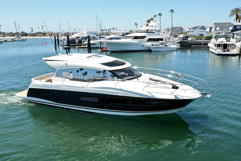 Slide: The Image of 2020 Prestige 460S yacht cruising in a sunny marina with palm trees and boats. - 16