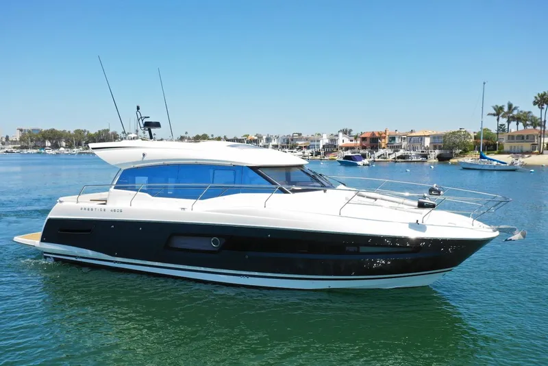 Slide: The Image of 2020 Prestige 460S yacht cruising in a scenic harbor under clear blue skies. - 4