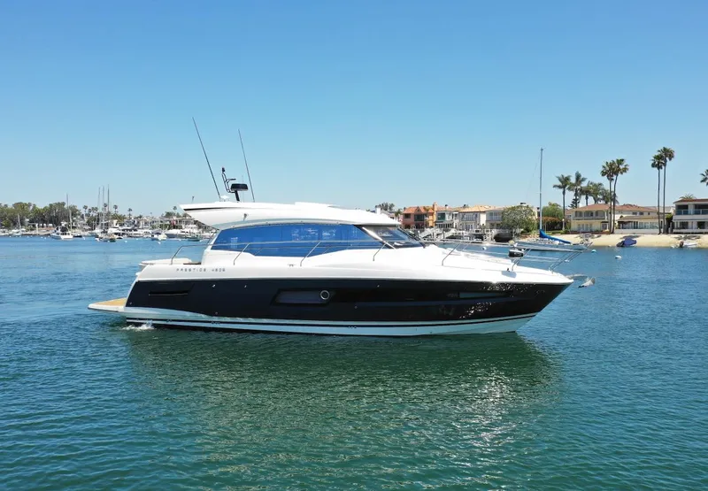 Slide: The Image of 2020 Prestige 460S yacht cruising in a sunny marina with waterfront homes in the background. - 5