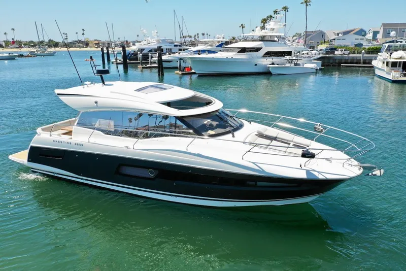 Slide: The Image of 2020 Prestige 460S yacht cruising in a marina with clear blue water and docked boats. - 6