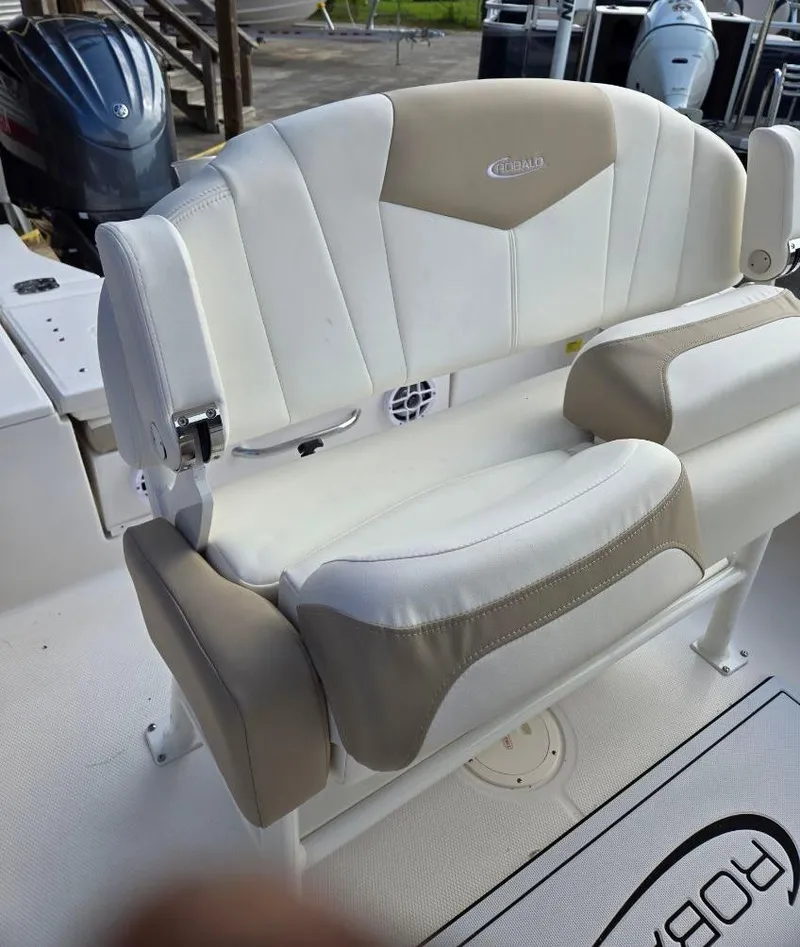 Slide: The Image of 2024 Robalo 246 Cayman boat seat, white and beige upholstery, on deck. - 10
