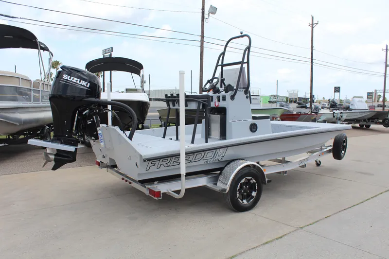 Slide: The Image of 2026 Freedom Boats EAGLE with outboard motor and storage compartments, parked on grass. - 5