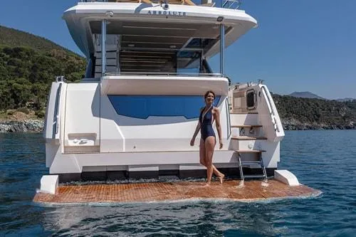 Slide: The Image of 2023 Absolute Fly Co Ownership yacht with woman on swim platform in scenic waters. - 9