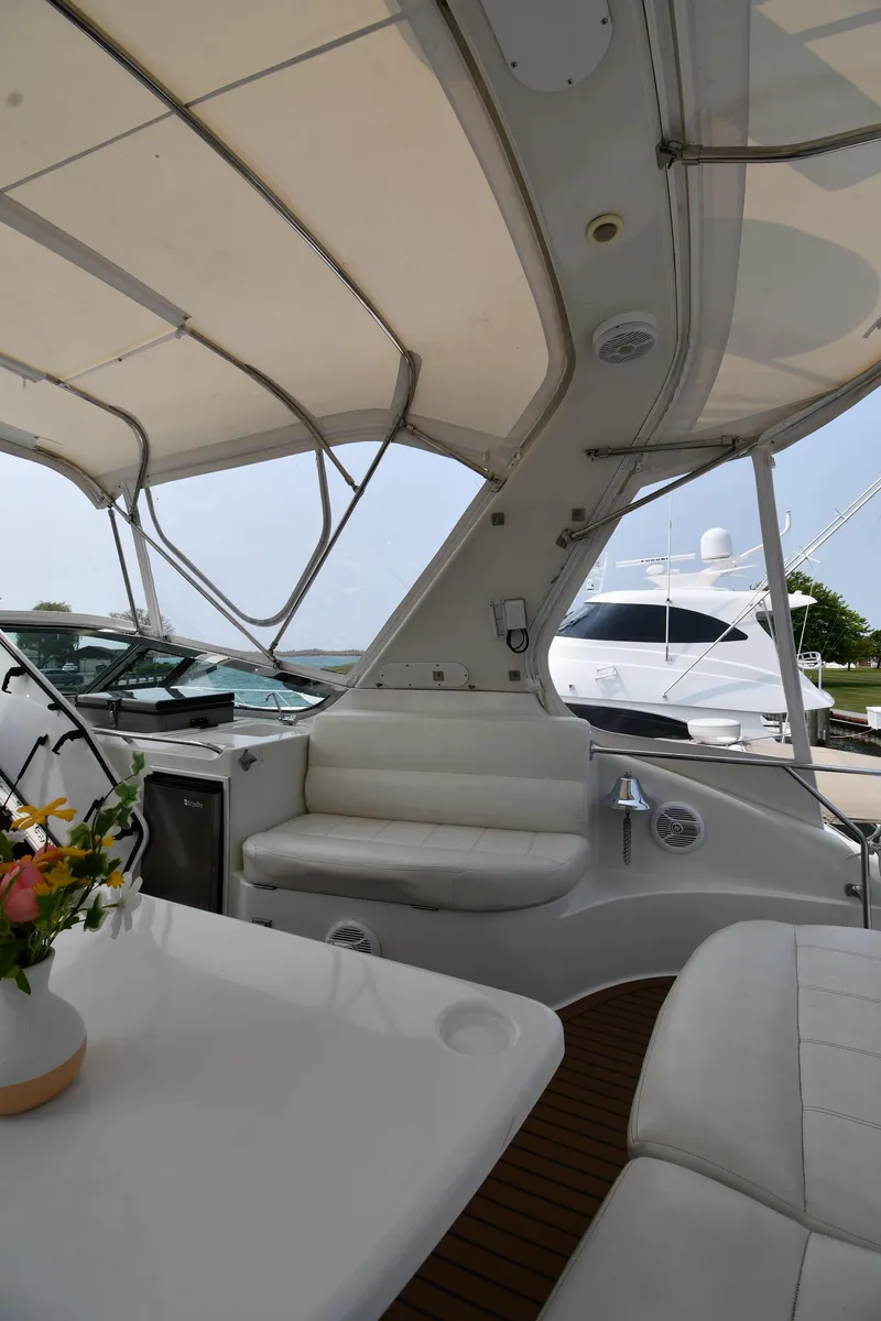 Slide: The Image of 1998 Carver 530 Voyager Pilothouse interior with white seating and table, docked near another yacht. - 27