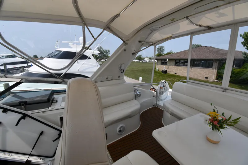 Slide: The Image of 1998 Carver 530 Voyager Pilothouse yacht interior with white seating and table, docked near a house. - 29