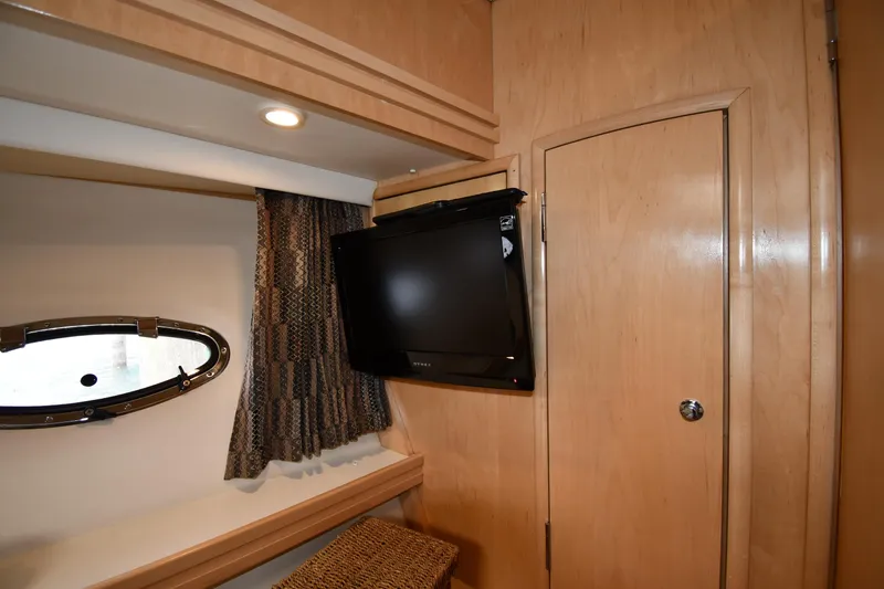 Slide: The Image of 1998 Carver 530 Voyager Pilothouse interior with TV, porthole, and wood paneling. - 44