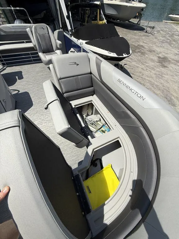 Slide: The Image of 2023 Bennington 22 SXSB pontoon boat with open storage compartments and gray seating. - 11