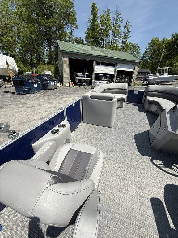 Slide: The Image of 2023 Bennington 22 SXSB pontoon boat with gray seating, docked near a green-roofed building. - 12