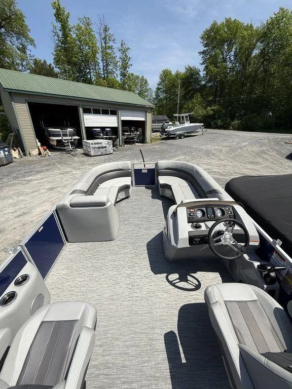 Slide: The Image of 2023 Bennington 22 SXSB pontoon boat with spacious seating and modern dashboard, parked outdoors. - 18