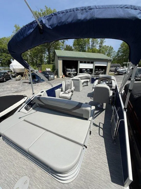 Slide: The Image of 2023 Bennington 22 SXSB pontoon boat with spacious seating and canopy, docked outdoors. - 23