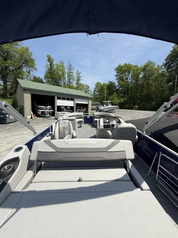 Slide: The Image of 2023 Bennington 22 SXSB pontoon boat with spacious seating, parked near a garage under a clear sky. - 25