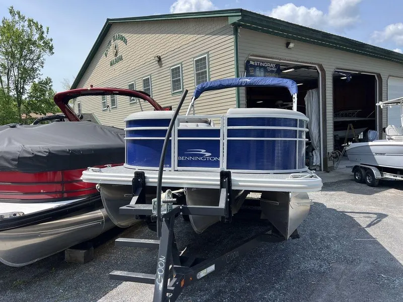 Slide: The Image of 2023 Bennington 22 SXSB pontoon boat parked outside a marina building. - 3