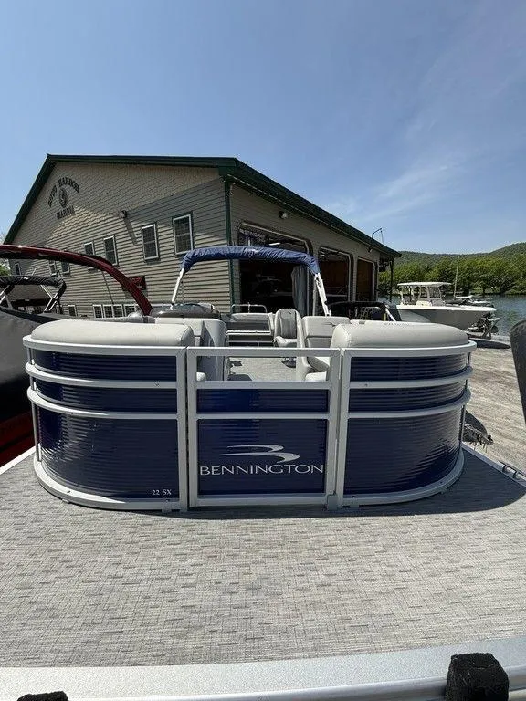 Slide: The Image of 2023 Bennington 22 SXSB pontoon boat docked near a lakeside building. - 5