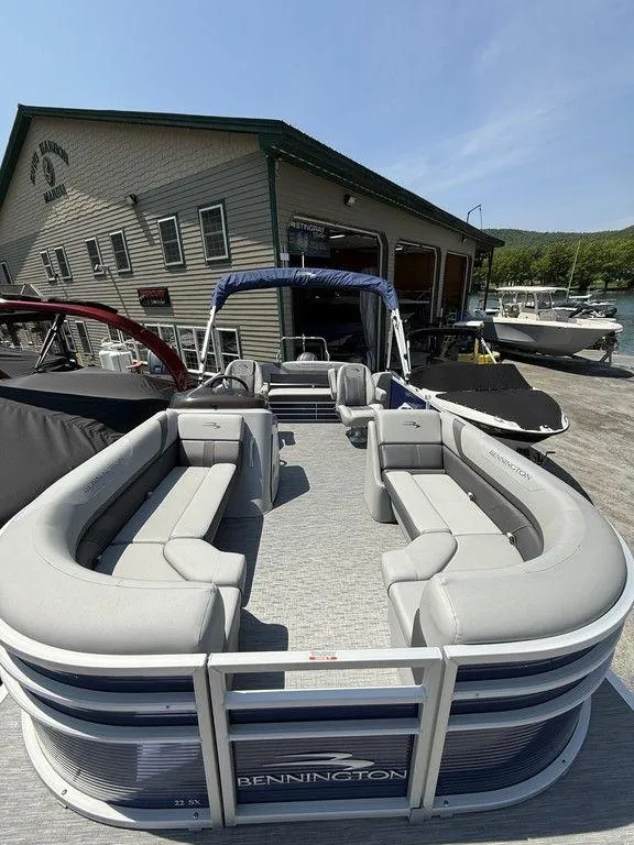 Slide: The Image of 2023 Bennington 22 SXSB pontoon boat with gray seating, docked near a boathouse. - 7