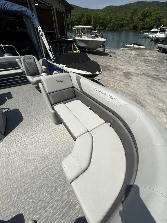 Slide: The Image of 2023 Bennington 22 SXSB pontoon boat with sleek seating, docked by a scenic lake. - 8