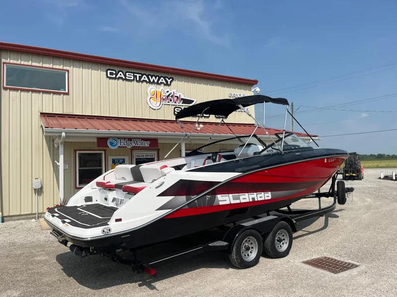 Slide: The Image of 2021 Scarab 255 ID boat on trailer outside Castaway building under clear blue sky. - 13