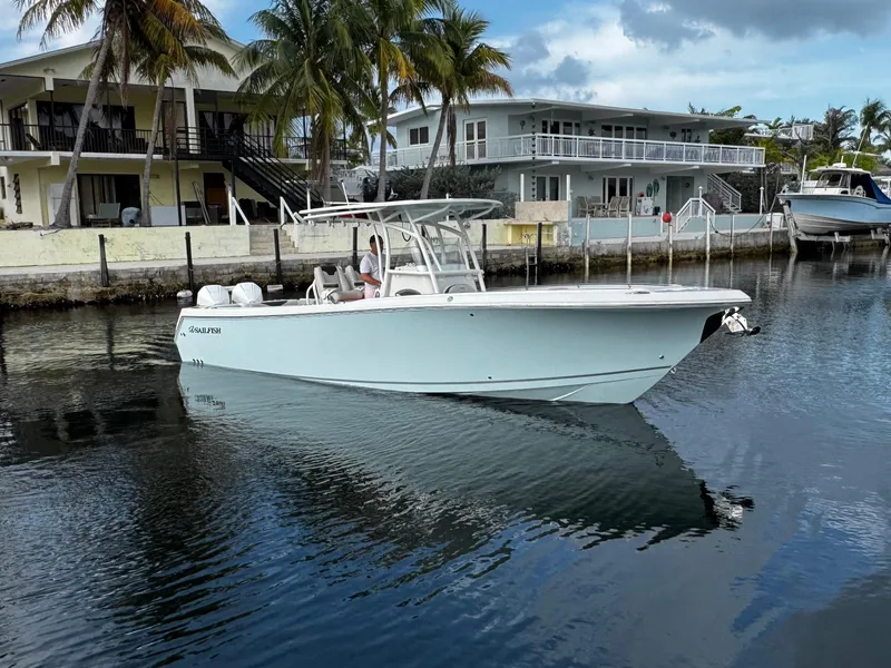 Slide: The Image of 2022 Sailfish 290 CC boat docked near waterfront homes with palm trees. - 1