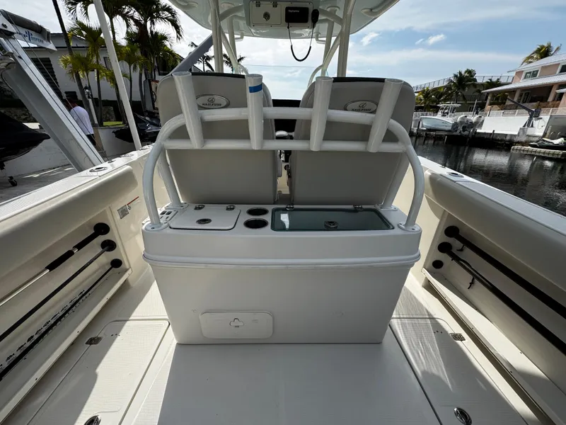 Slide: The Image of 2022 Sailfish 290 CC boat interior with seating and storage, docked by a marina. - 12