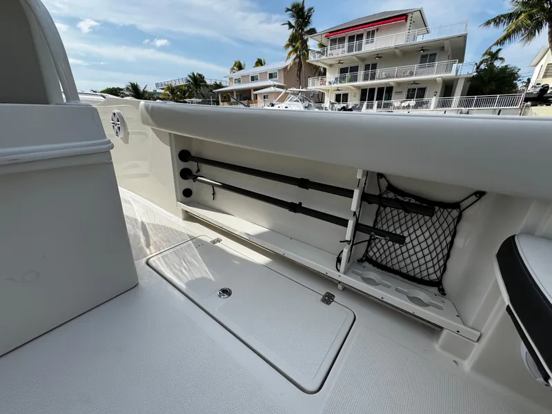 Slide: The Image of 2022 Sailfish 290 CC boat interior with rod storage and netting, docked near waterfront homes. - 13
