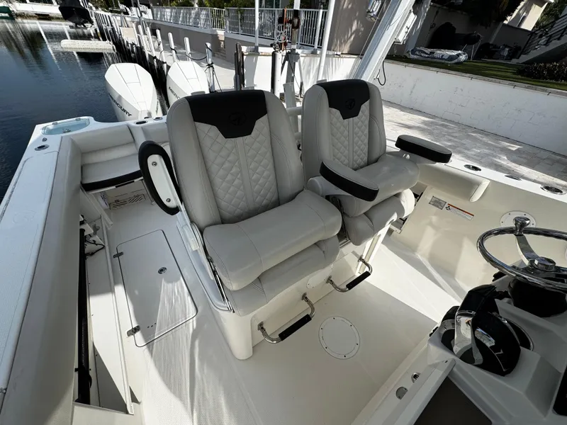 Slide: The Image of 2022 Sailfish 290 CC boat interior with dual cushioned seats and steering wheel. - 17