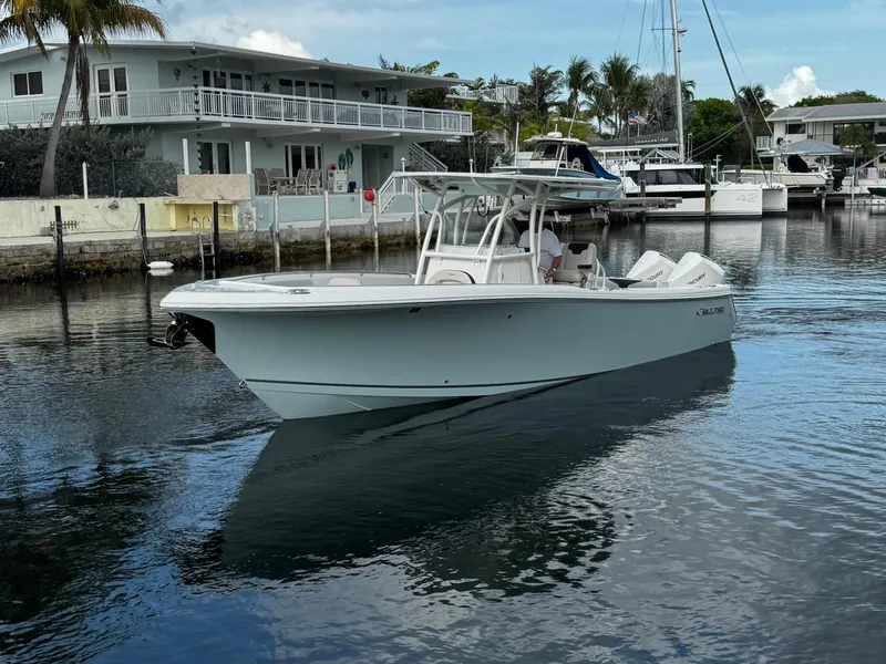 Slide: The Image of 2022 Sailfish 290 CC boat docked near waterfront homes and yachts. - 2