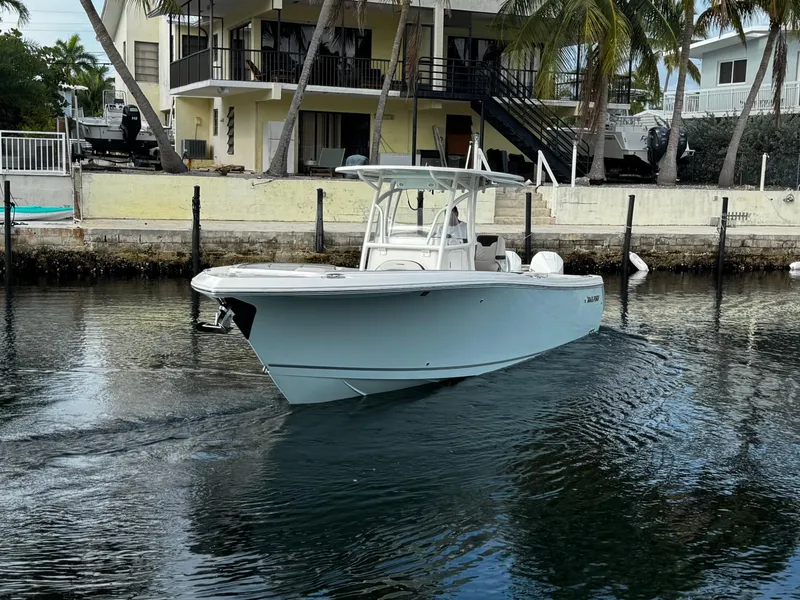 Slide: The Image of 2022 Sailfish 290 CC boat on calm water near a waterfront house. - 3