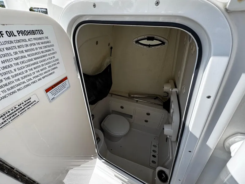 Slide: The Image of 2022 Sailfish 290 CC boat interior with compact marine toilet and storage area. - 36