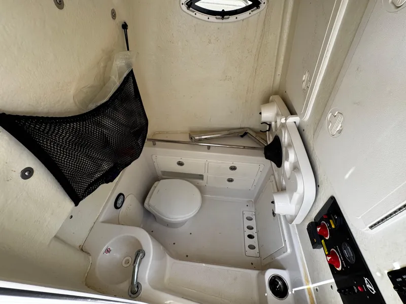 Slide: The Image of 2022 Sailfish 290 CC boat interior with compact bathroom and storage features. - 37