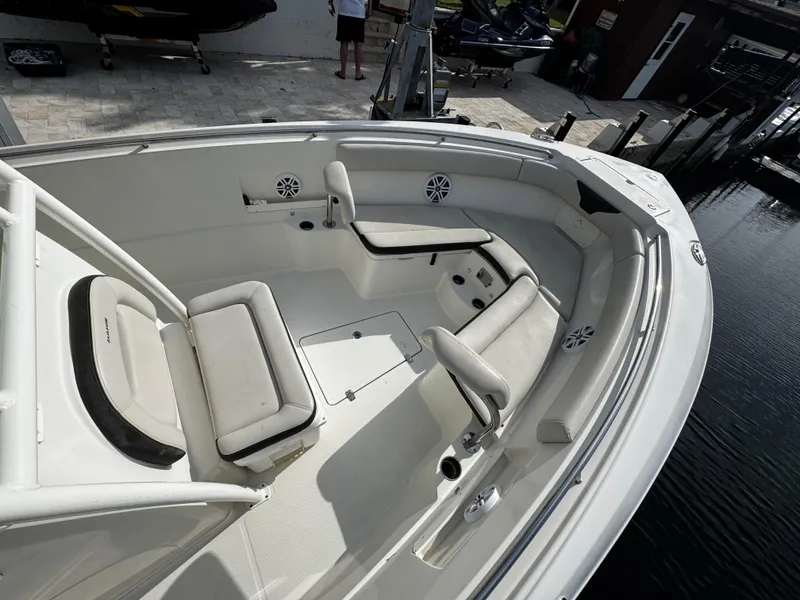Slide: The Image of 2022 Sailfish 290 CC boat interior with cushioned seating and speakers, docked by the water. - 8