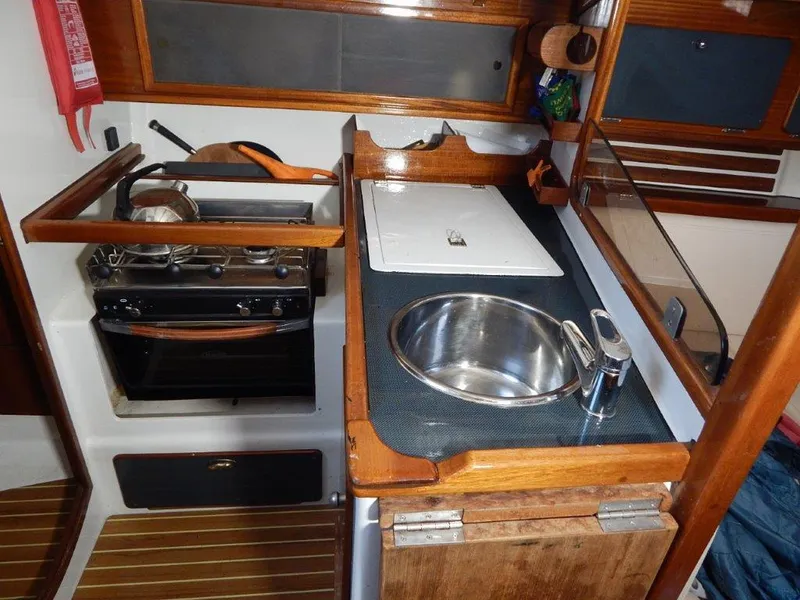 Slide: The Image of Compact boat kitchen with stove, sink, and wooden cabinetry in a 2003 Custom 38 C/R model. - 25