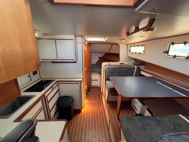 Slide: The Image of Interior of a 2001 Norstar 301 boat featuring a kitchen and dining area with wood accents. - 35