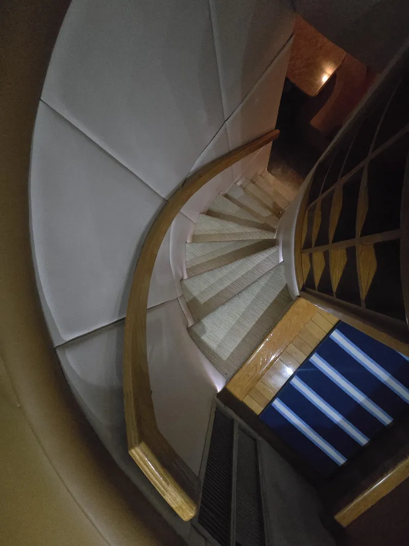 Slide: The Image of Curved staircase inside 1994 Hatteras 82 Convertible yacht, featuring wooden handrails and modern design. - 18
